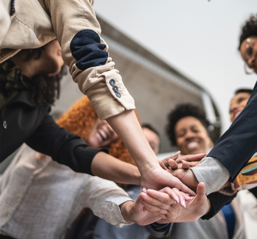 A community of diverse people with their hands in the center